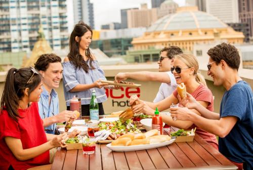 a group of people sitting around a table eating food at Space Hotel in Melbourne