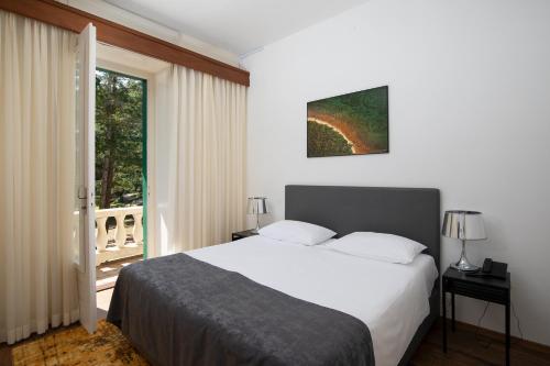 a bedroom with a large white bed and a window at Brijuni Hotel Neptun in Fažana