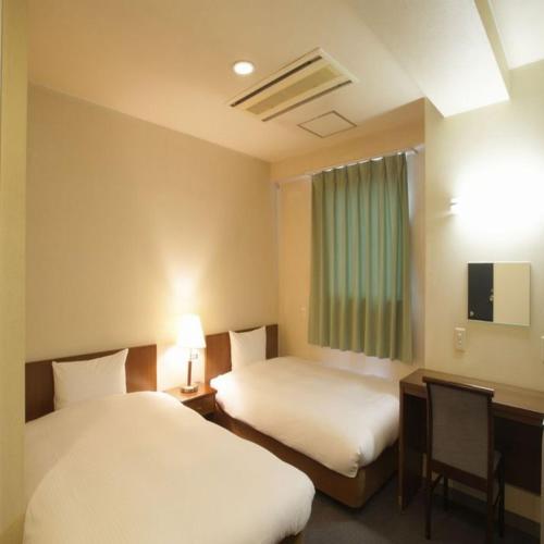 a hotel room with two beds and a window at Hotel Green Palace in Sendai