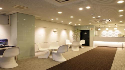 a waiting room with white chairs and a table at Hotel Green Palace in Sendai