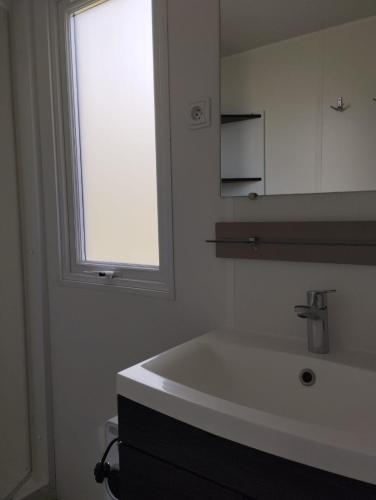 a white bathroom with a sink and a window at Olivier 64 in Valras-Plage