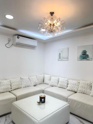 a living room with a white couch and a chandelier at Velmora 1BR Apartment 13 in Abu Dhabi