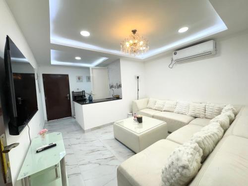 a living room with a white couch and a tv at Velmora 1BR Apartment 13 in Abu Dhabi