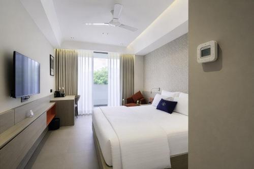 a hotel room with a bed and a television at Grand Continent Hotel, Near Sector 44, Gurugram in Gurgaon