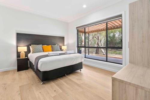 a bedroom with a large bed and a large window at Riversands Rest Accommodation Scenic Riverfront Cottages, Paringa in Renmark