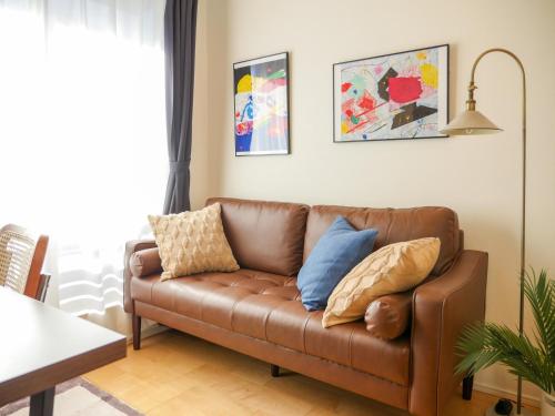a brown couch in a living room with pillows on it at MSTAY池袋one in Tokyo