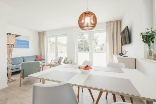 a white living room with a table and chairs at Boddenruh in Fuhlendorf