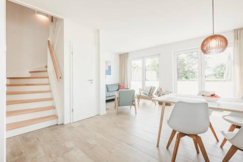 a white living room with a table and chairs at Boddenruh in Fuhlendorf