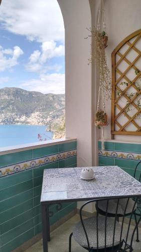 a table and chairs in a room with a window at Panoramic Sea View Balcony Apartment in the Heart of Praiano, Casa Mimì Junior in Praiano