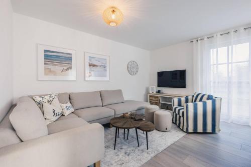 a white living room with a couch and a table at Kranichkieker in Zingst