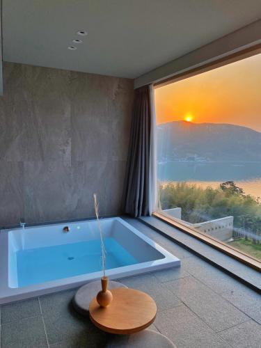a large bath tub in a room with a large window at Hotel SANG SANG & Private SANG SANG POOL VILLA in Geoje