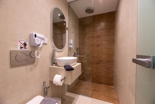 a bathroom with a sink and a mirror and a shower at ATH Airport Suites Free Shuttle From And To Athens Airport in Spata