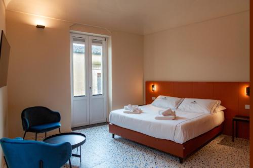 a hotel room with a bed and two chairs at Ghibellini Rooms in Palazzolo Acreide