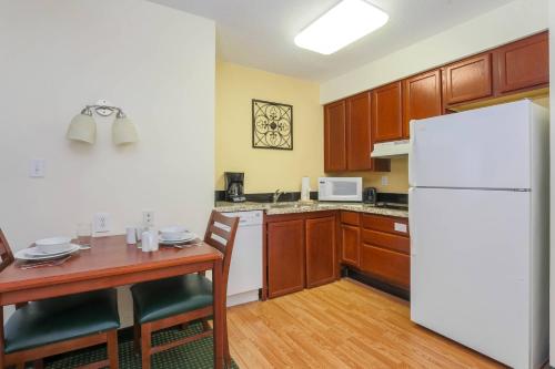 a kitchen with a table and a white refrigerator at Residence Inn by Marriott Oklahoma City South in Oklahoma City