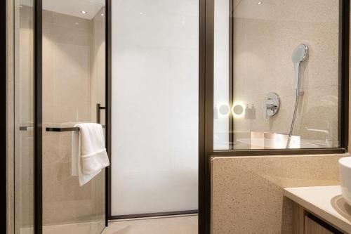 a bathroom with a shower with a glass door at Grand Continent Hotel, Near Sector 44, Gurugram in Gurgaon