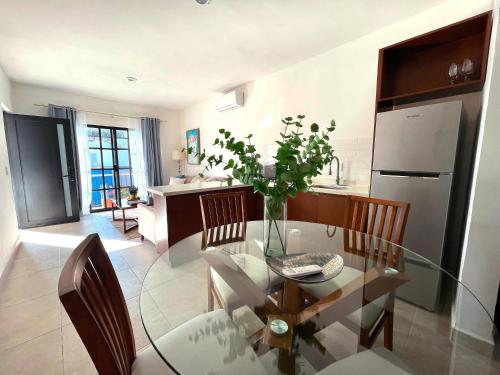 a dining room with a glass table and a kitchen at Casa DOS21 Boutique Apartments Playa Sur in Mazatlán