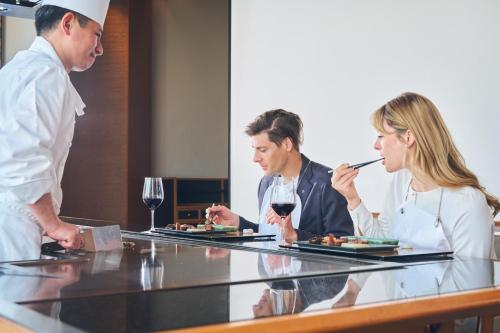 three people sitting at a table with food and wine at Imperial Hotel Osaka in Osaka