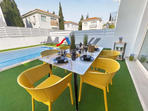 a table and chairs on a patio with a pool at Villa Allegra in Protaras