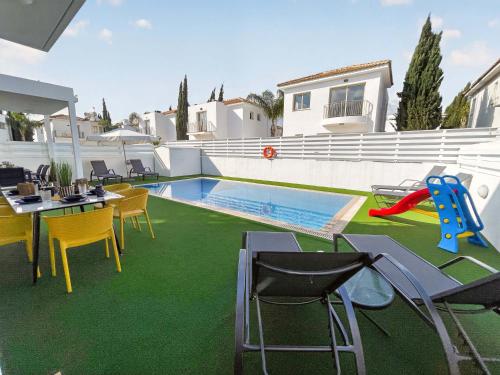 a backyard with a pool and chairs and a table at Villa Allegra in Protaras