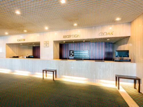 a hotel lobby with a reception counter and two benches at Yatsushiro Grand Hotel in Yatsushiro