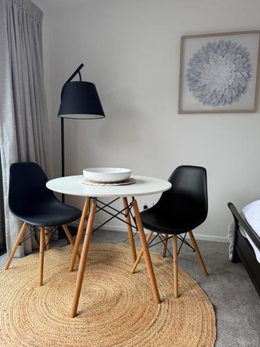 a table and chairs in a living room with a lamp at Cozy Pakura Pad in Te Awamutu
