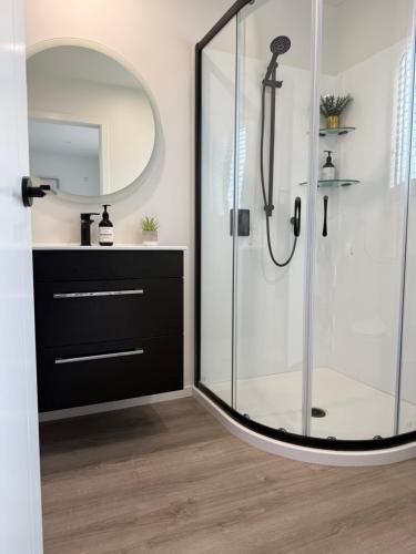 a bathroom with a glass shower with a mirror at Cozy Pakura Pad in Te Awamutu