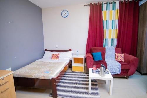 a small room with a bed and a chair at Vine Suites Mbarara - 1 Bed Studio Apartment Near LDC & City Centre - Quiet & Convenient in Mbarara
