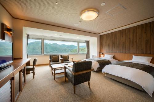 a hotel room with two beds and a desk and a television at Yumoto Kissho in Osaki