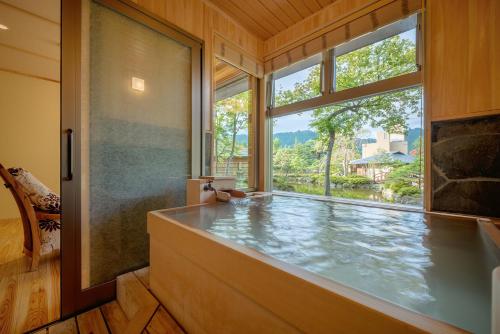 a large bathroom with a tub and a large window at Yumoto Kissho in Osaki