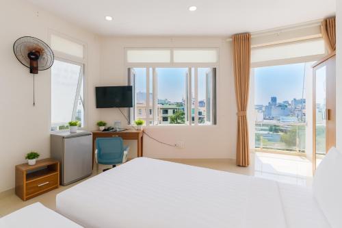 a bedroom with a bed and a desk and windows at Lunar Stay HCM in Ho Chi Minh City
