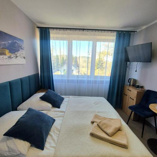 a bedroom with two beds with blue curtains and a window at Willa Elżbieta - komfortowy wypoczynek, znakomite recenzje Gości in Karpacz