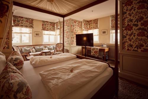 a bedroom with two beds and a couch and a television at Hotel Detmolder Hof in Detmold