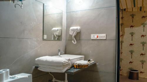 a bathroom with a sink and a mirror and towels at Desert Horizon Luxury Resort &Camp in Jaisalmer