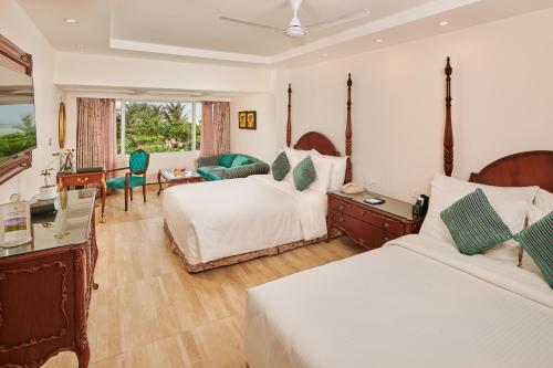 a hotel room with two beds and a desk at Mayfair Heritage in Puri