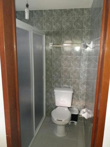 a small bathroom with a toilet and a shower at Room in Cancun Stadium in Cancún