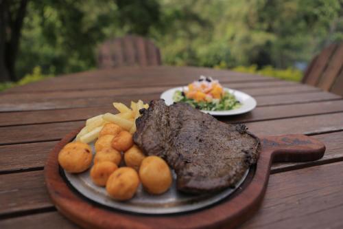 a plate of steak and potatoes on a wooden table at HOTEL LA SELVA Reserva in La Vega