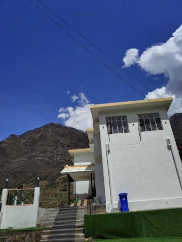 a white house with stairs in front of a mountain at Mandola Stays in Chamoli