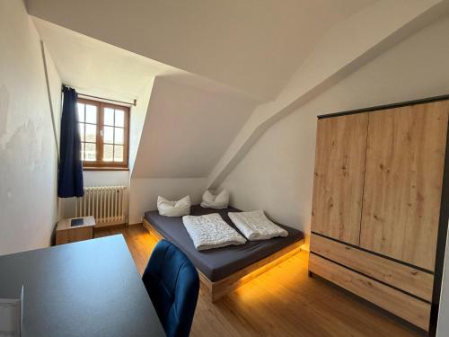a small room with a bed and a wooden cabinet at CVJM Peregrinus Herberge in Görlitz