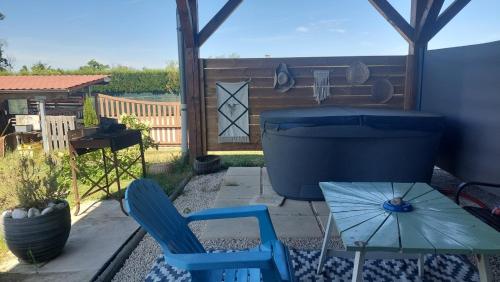 a patio with two blue chairs and an umbrella at Gîte nature et spa in Saint-Sulpice