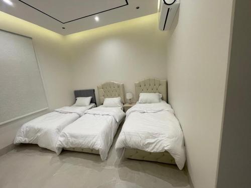 two beds in a room with white walls at قوت in Abha