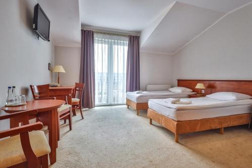 a hotel room with two beds and a desk at Eden in Rydzyna