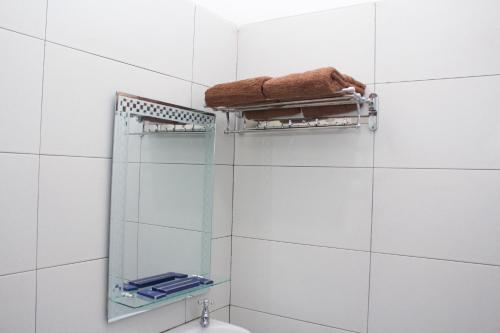 a white tiled bathroom with a mirror and a sink at Salak Cozzy Stay Managed by Salak Hospitality in Kamparganya