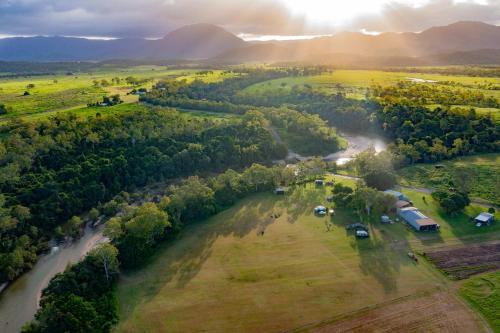an aerial view of a field with a river and trees at Echidna by Tiny Away in Thoopara