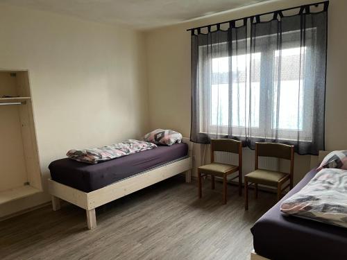 a room with two beds and chairs and a window at Pension Highway - Bünde Carl Diem Straße 46 in Bünde