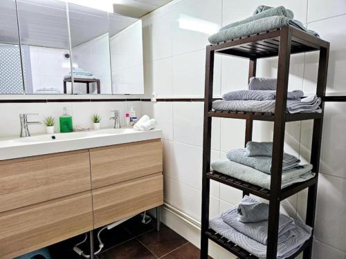 a bathroom with a sink and a shelf with towels at Le Canut Duviard - proche métro Croix-Rousse in Lyon