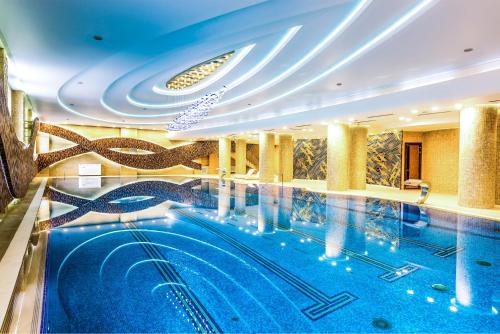 una gran piscina en un hotel con techo en Jumbaktas Astana Hotel, en Astana
