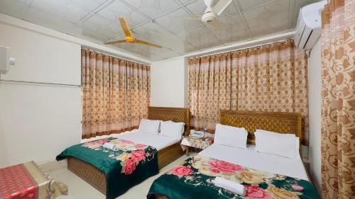 a bedroom with two beds and a ceiling fan at Hotel Labbaik Three College Gate in Dhaka
