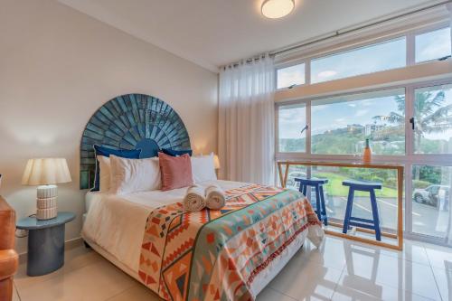 a bedroom with a bed and a large window at Alfomada in Umdloti