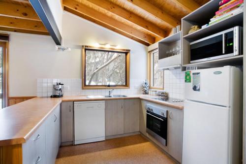 a kitchen with white appliances and a wooden ceiling at Welkuminn in Dinner Plain
