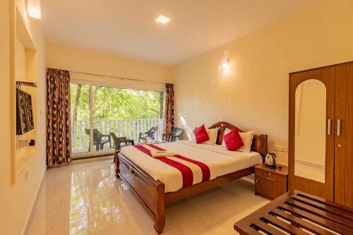 a bedroom with a bed and a large window at Riyan Valley Resort in Ooty